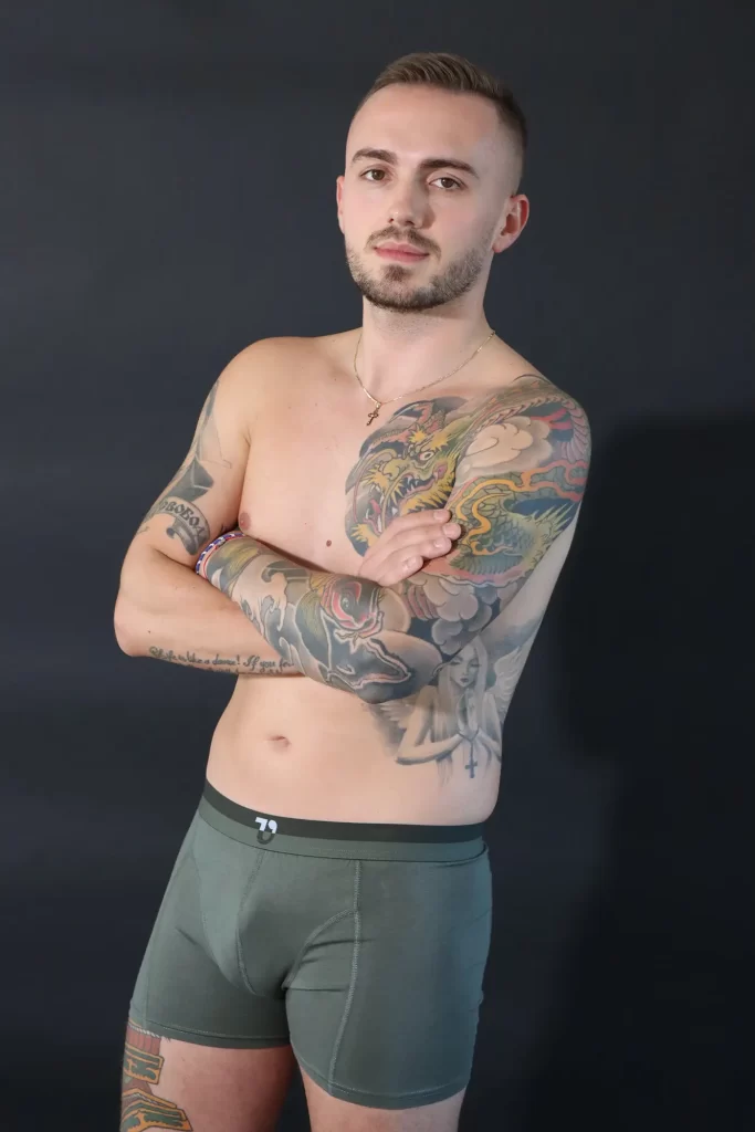 Mann mit Tattoos in olive-grünen Trunks