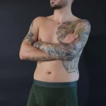 Mann mit Tattoos trägt dunkel-grüne Trunks