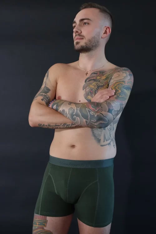 Mann mit Tattoos trägt dunkel-grüne Trunks